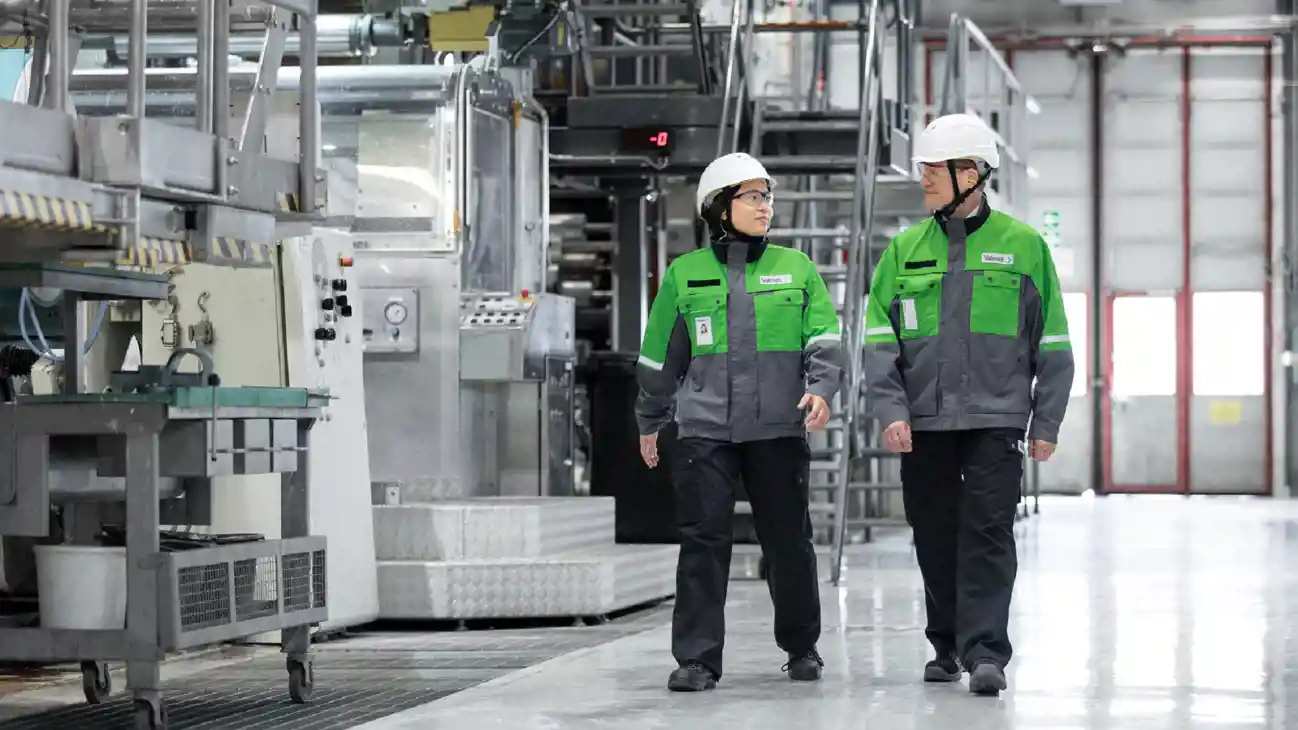 Two people working on a paper machine