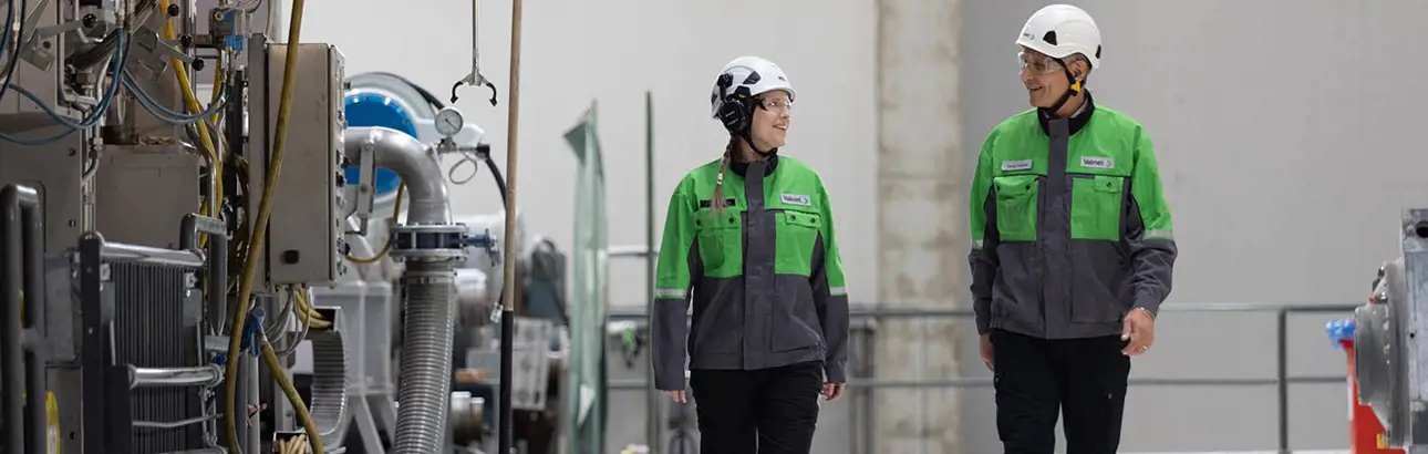 Two Valmet workers walking beside the pilot paper machine at Valmet Paper Technology Center