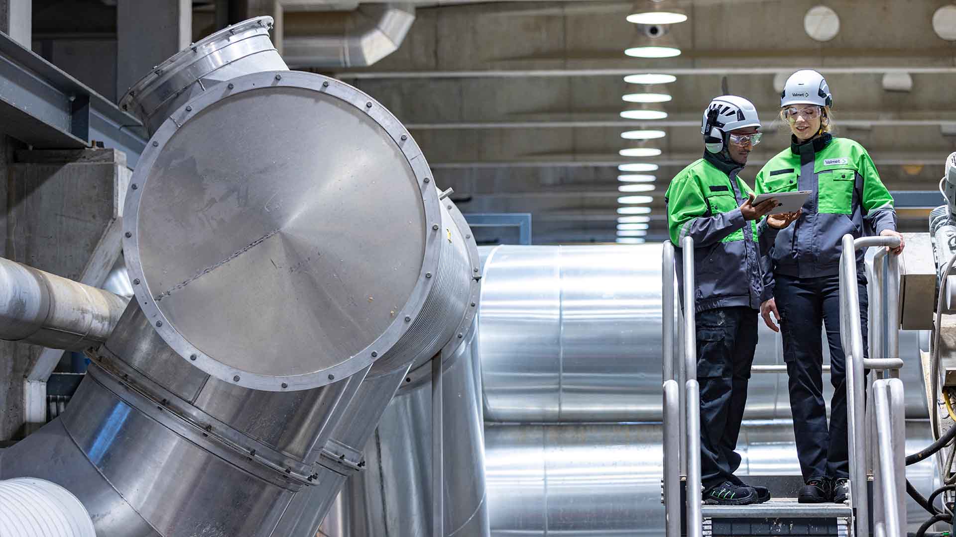 Valmet employees standing on top of a walkway inside Valmet's own pilot factory in Jyväskylä, Finland.