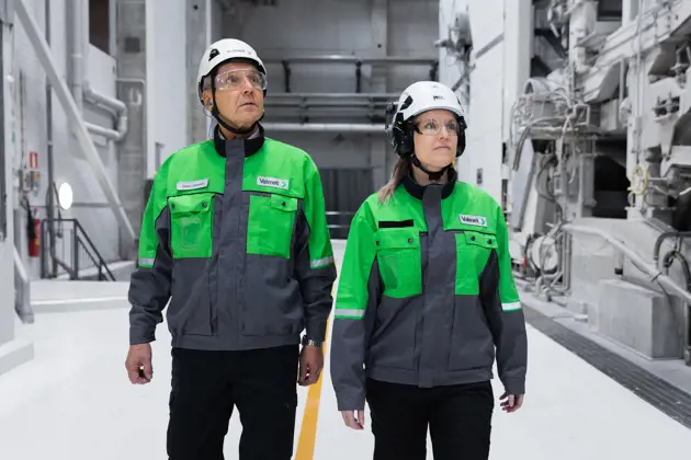 Two Valmet workers walking alongside a board machine