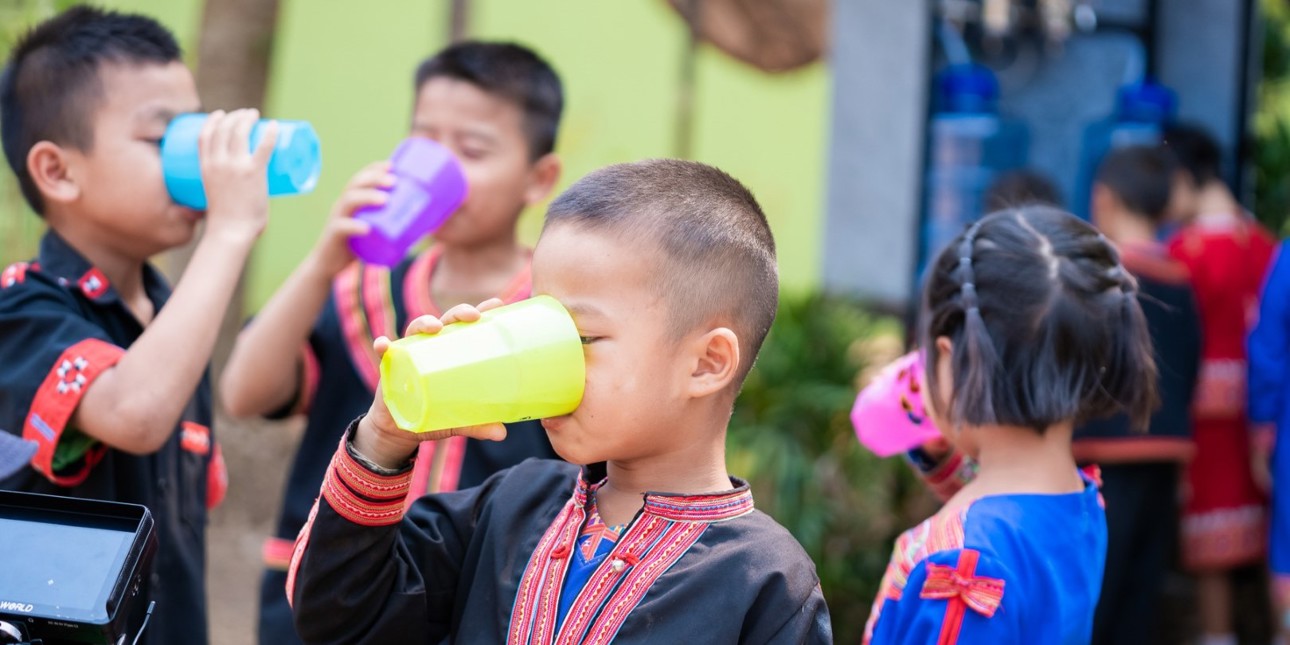 Children drinking clean and safe water from coloful cups.