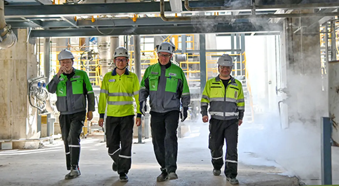 Four workers in pulp mill with helmets